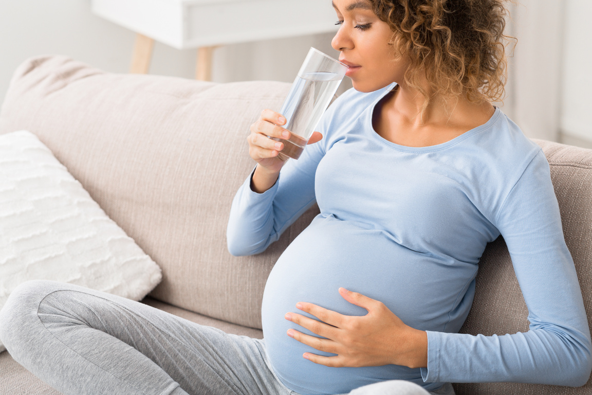 Pregnancy and hydration. Expectant woman drinking water